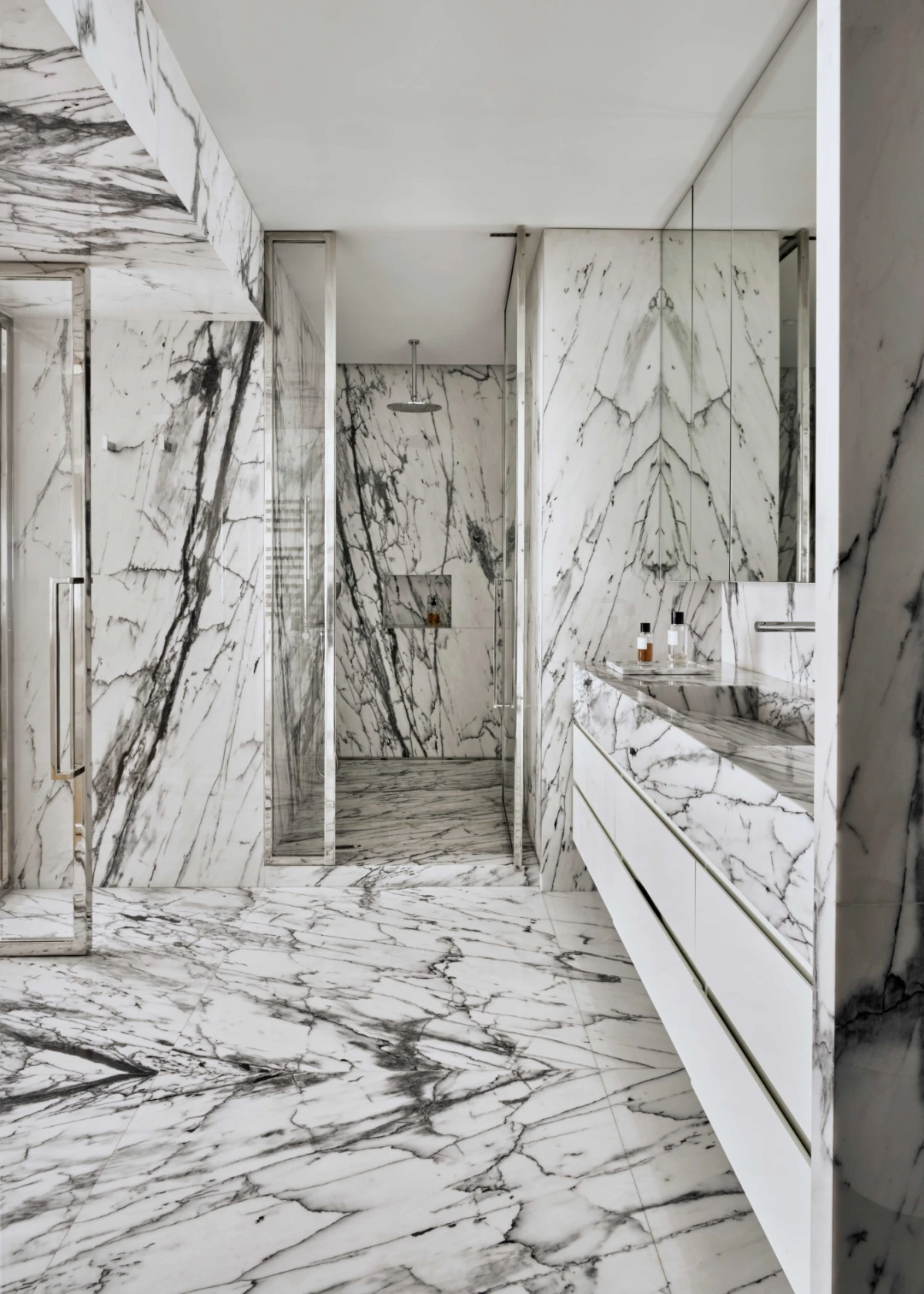 White marble bathroom with walk-in shower and sleek modern fittings.