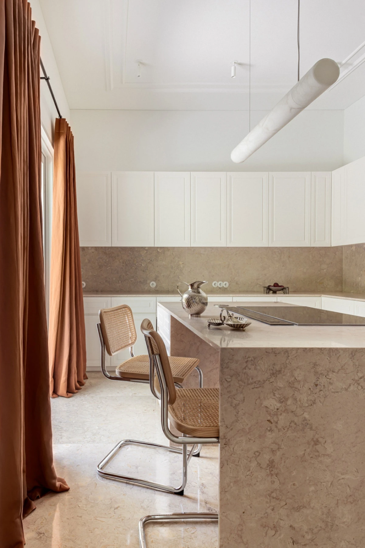 Interior design kitchen in lioz marble in serene tones with an alabastar ceiling lamp and rail curtains