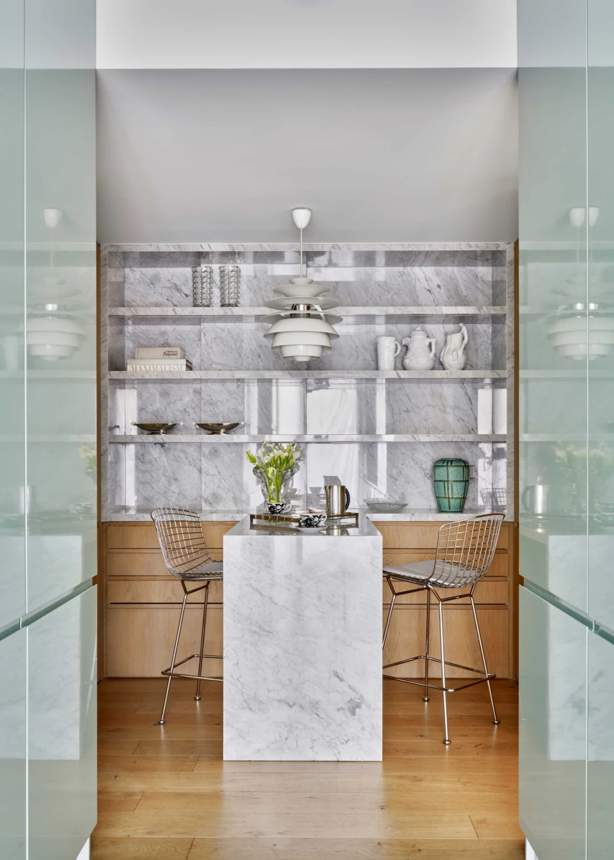 Contemporary green kitchen design with modern marble island and minimalist shelving.